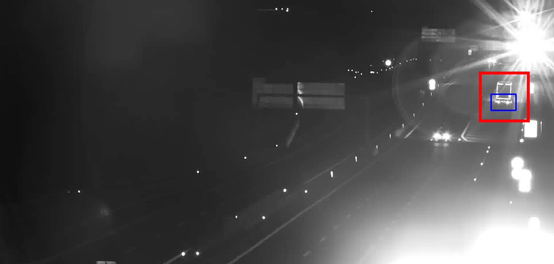 Stopped vehicle detected at night near a sign gantry, close to a bright light source