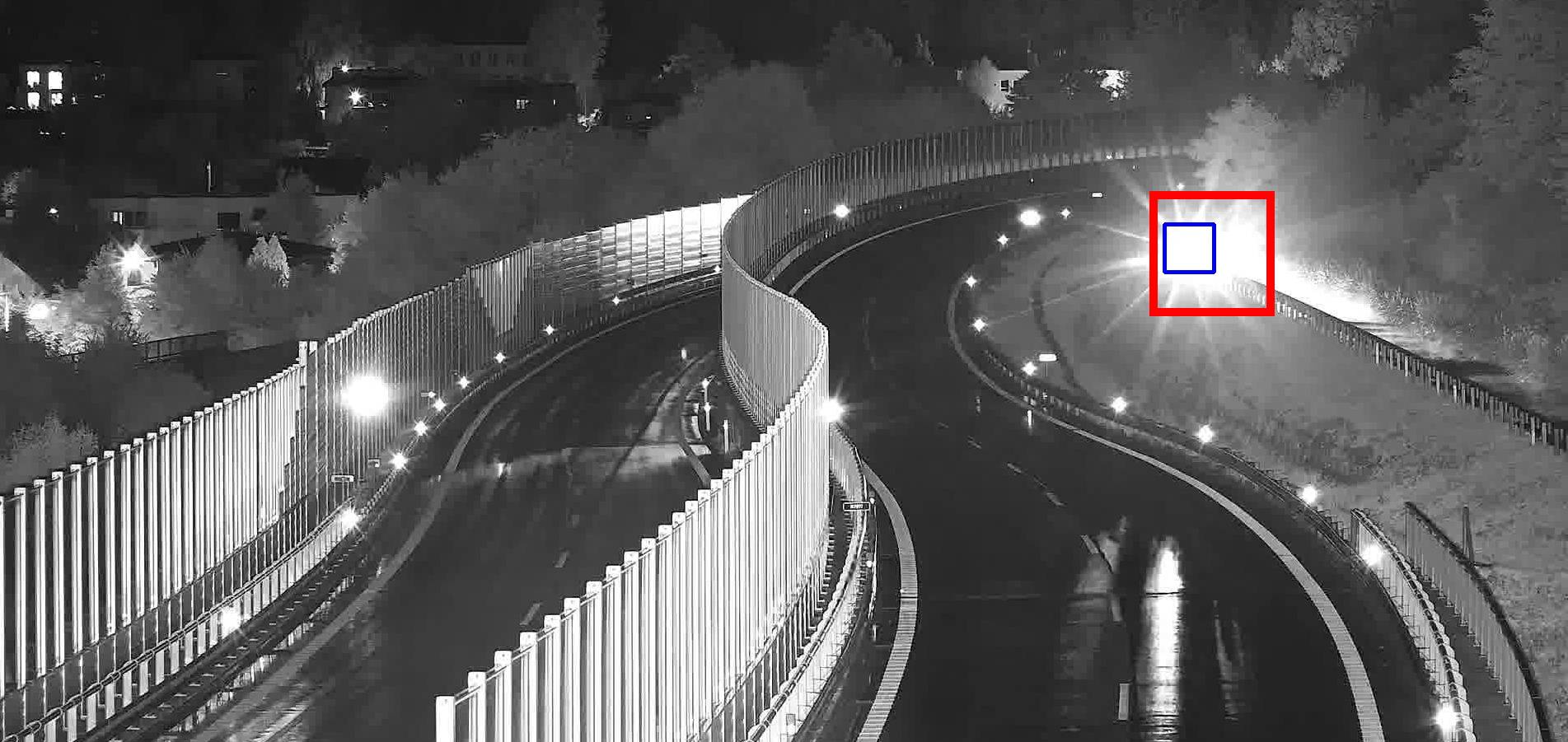 Infračervený noční pohled na zatáčející rychlostní silnici se stojícím vozidlem detekovaným za protihlukovými stěnami
