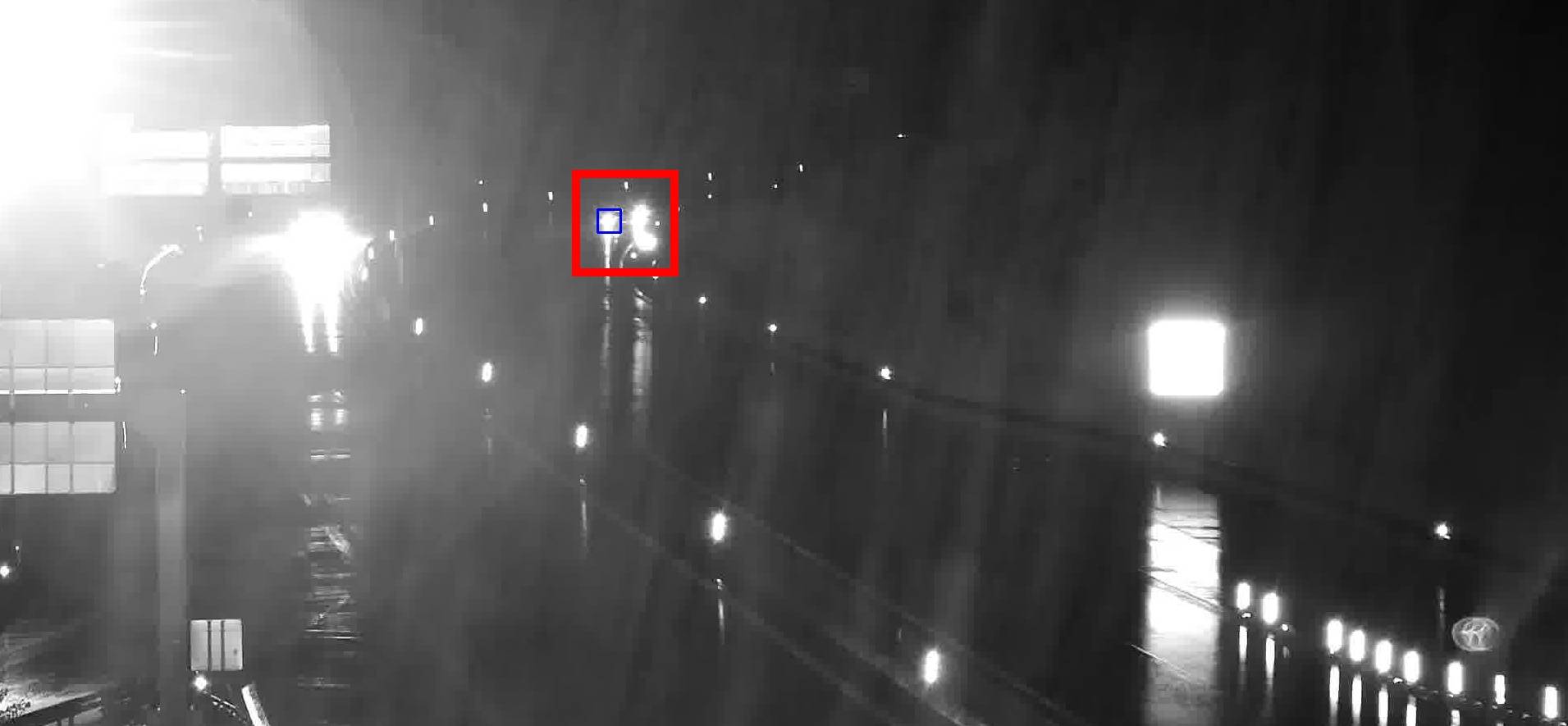 Stopped vehicle detected at night on a wet road, its lights blending with other static lights