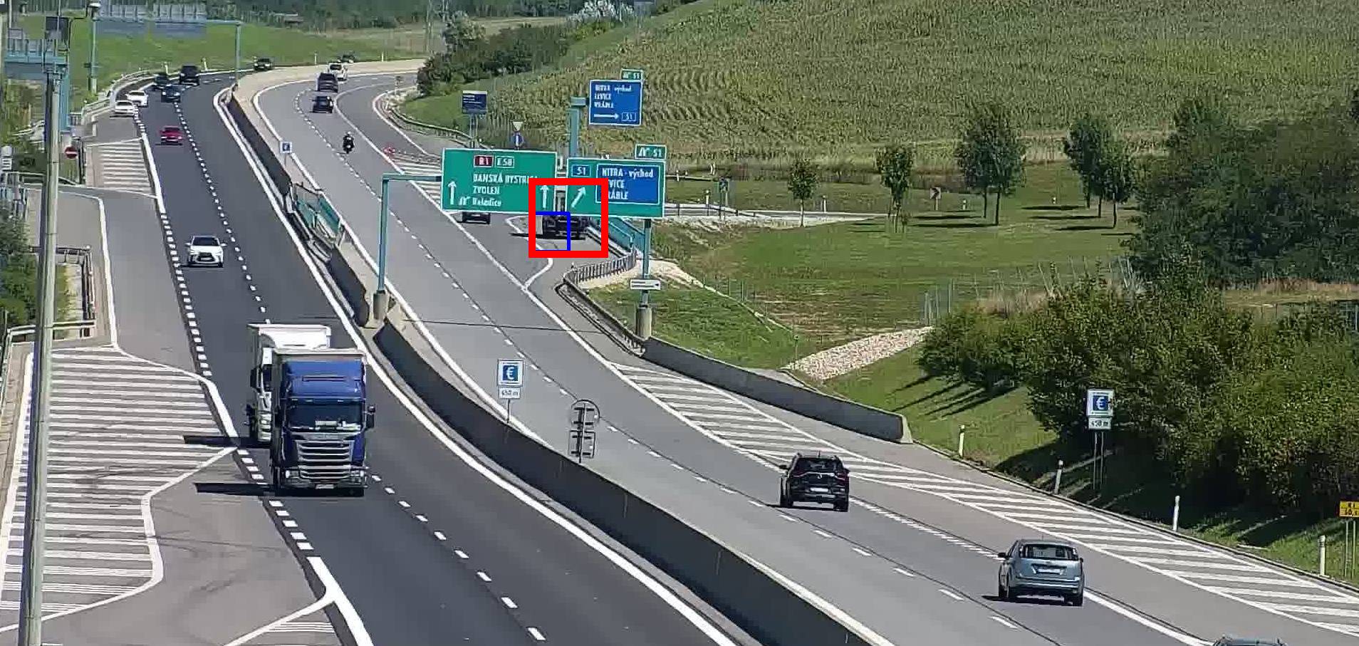 Stojící nákladní vozidlo z větší části skryté za směrovou tabulí na rychlostní silnici