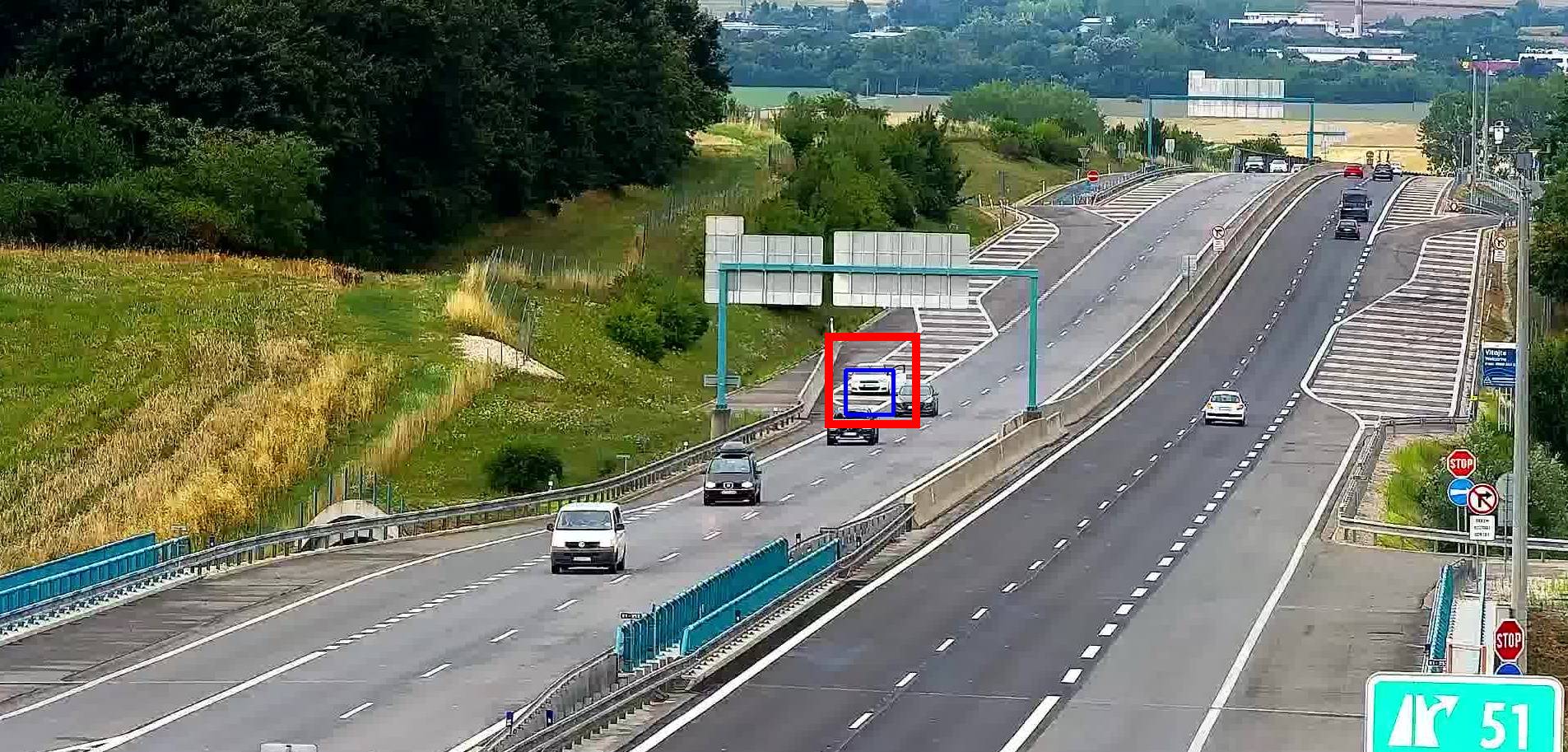 Auto stojící pod portálem dopravního značení na rychlostní silnici, detekované za denního světla