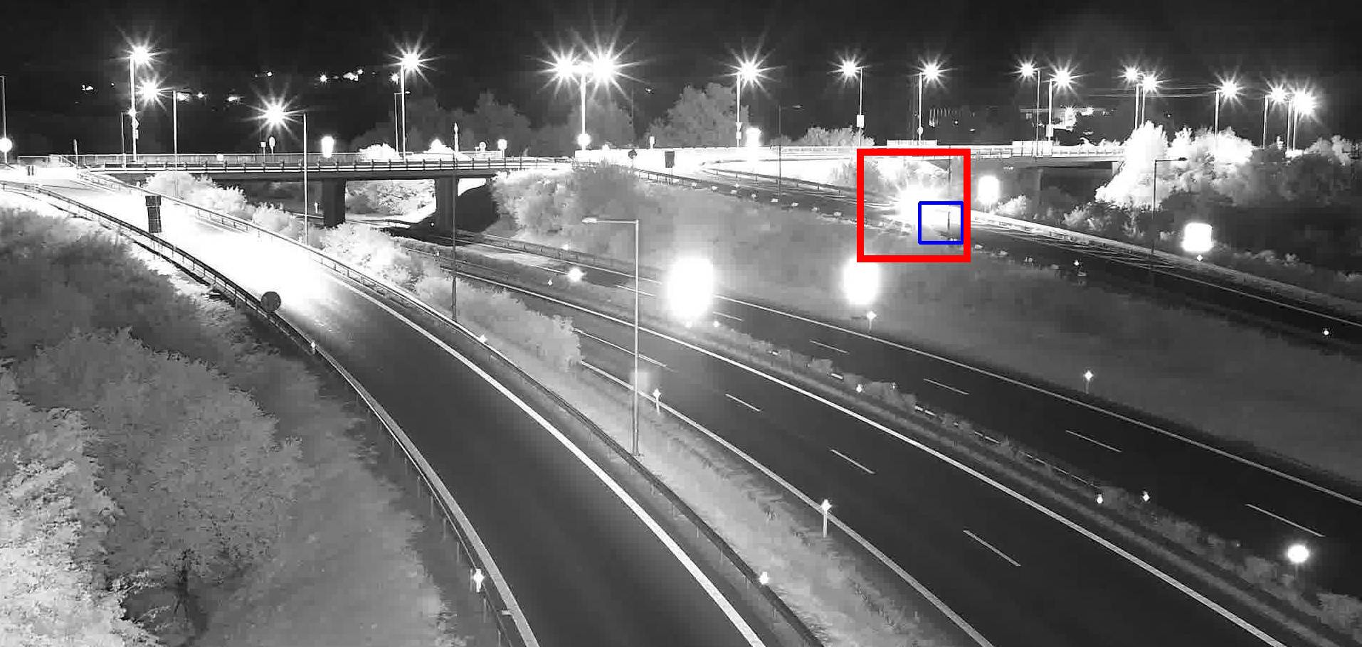 Car stopped near an overpass at night, its lights blending into the street lighting