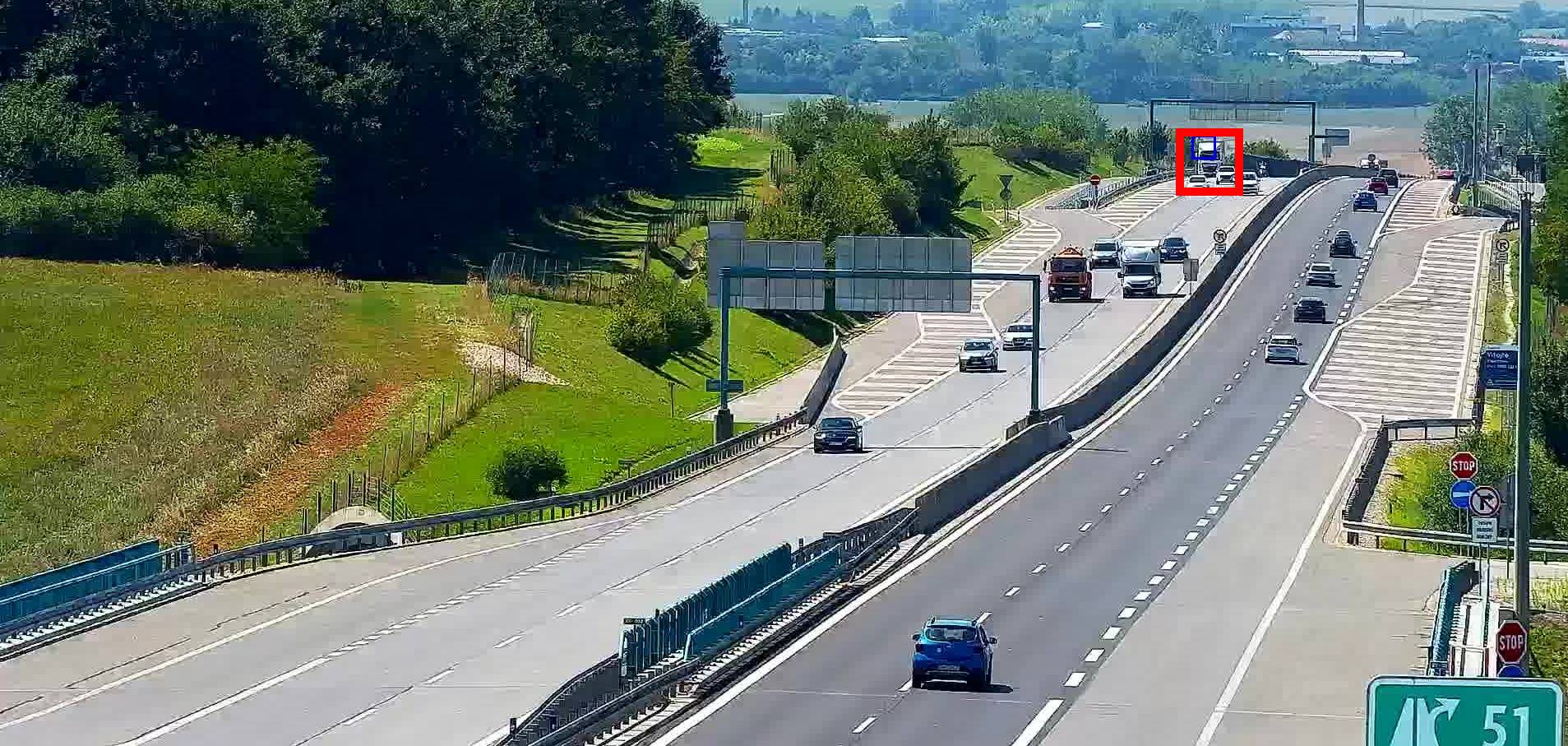 Distant stopped vehicle detected far from the traffic camera on a busy expressway
